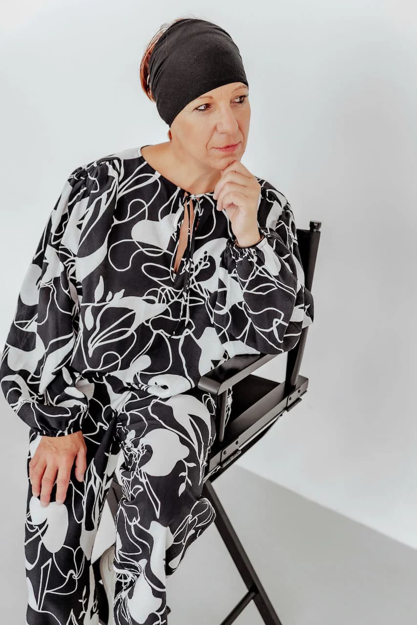 Woman in black and white abstract floral pattern outfit seated on director's chair
